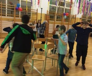 Uczniowie tańczą wokół ustawionych w kole krzeseł