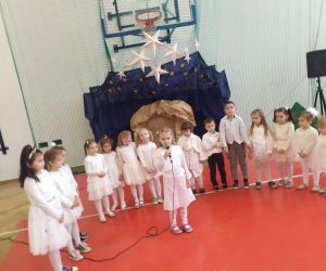 Dziewczynka recytuje wiersz o tematyce świątecznej, dzieci śpiewają kolędy