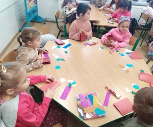 Dzieci przy stolikach czekają na materiały do wykonania kartek