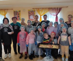 Zdjęcie przedstawia grupę osób, dorosłych i dzieci pozujących do zdjęcia.