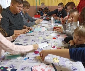 Zdjęcie przedstawia grupę dzieci w trakcie warsztatów plastycznych. 