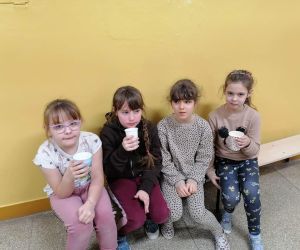 Uczennice siedzą na ławeczce i piją czekoladowy napój