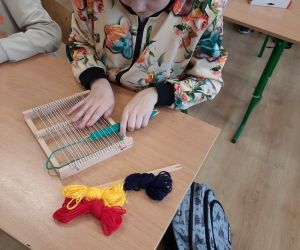 Dziewczynka pracuje z krosnem tkackim