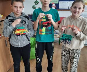 Uczniowie trzymają rzeczy wykonane na krośnie