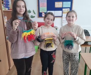 Dziewczynki prezentują prace wykonane na krośnie