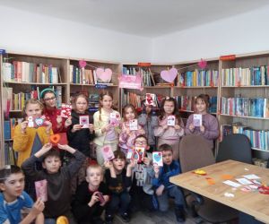 Zdjęcie przedstawia dzieci pozujące do zdjęcia wraz z kartkami walentynkowymi.