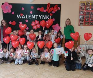 Zdjęcie przedstawia grupę dzieci pozujących do zdjęcia z balonami w kształcie serc.