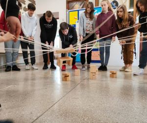 Grupa osób wewnątrz budynku, gra w zabawę integracyjną przy użycia 