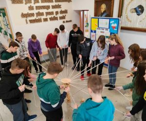 Grupa osób wewnątrz budynku, gra w zabawę integracyjną przy użycia 
