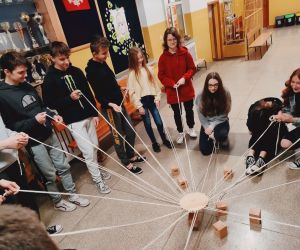 Grupa osób wewnątrz budynku, gra w zabawę integracyjną przy użycia 