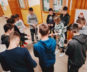 Grupa osób wewnątrz budynku, gra w zabawę integracyjną przy użycia 