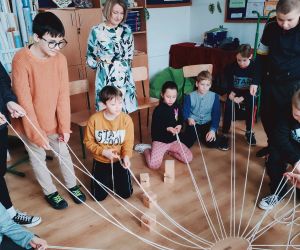 Grupa osób wewnątrz budynku, gra w zabawę integracyjną przy użycia 