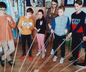 Grupa osób wewnątrz budynku, gra w zabawę integracyjną przy użycia 