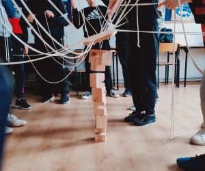 Grupa osób wewnątrz budynku, gra w zabawę integracyjną przy użycia 