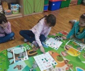 Dziewczynki siedzące na dywanie dopasowują elementy układanki