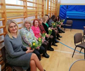 Panie siedzą na krzesłach z kwiatami w dłoniach