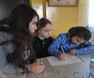 Zdjęcie przedstawia trzy dziewczynki piszące na kartce.