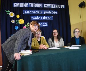 Zdjęcie przedstawia trzy dorosłe kobiety, trzy z nich siedzą przy stoliku jedna stoi.