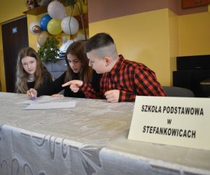 Zdjęcie przedstawia trójkę dzieci rozwiązujących zadanie.