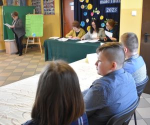 Zdjęcie przedstawia dzieci i dorosłych wewnątrz budynku.