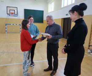 Uczennica odbiera dyplom i nagrodę za udział w konkursie „Kartka Wielkanocna”.