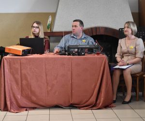 Trzy osoby wewnątrz budynku siedzą przy stole.