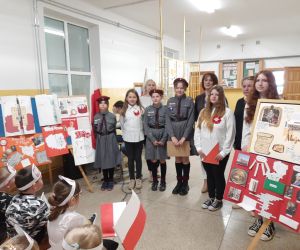 Uczennice z panią Dyrektor i nauczycielkami na wspólnym zdjęciu, w tle prace konkursowe