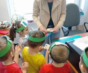 Pani bibliotekarka wręcza dzieciom zakładki do książek oraz naklejki