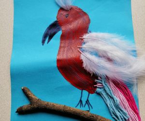 kolaż, papuga namalowana, doklejone pióra na głowie i skrzydłach, ogon z kolorowej włóczki. Drewniany kijek.