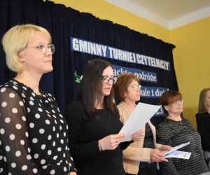 Na zdjęciu widocznych jest pięć osób dorosłych, jedna z nich czyta wyniki.