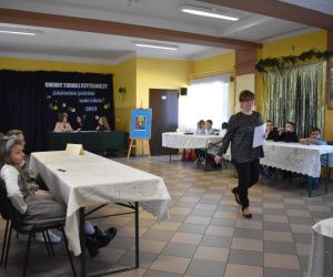 Zdjęcie przedstawia salę na której umieszczone są stoły przy których siedzą dzieci.