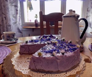 Sernik w kolorze fioletowym, obok biały imbryk, prawdopodobnie z herbatą o smaku lawendy