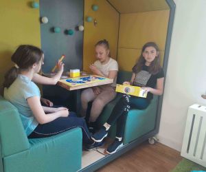 Cztery uczennice grają w grę planszową przy stoliku