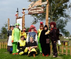 Postacie w bajkowych strojach w tle drewniany płot i zielone rośliny