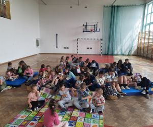 Uczniowie siedzą w grupach i czytają książki