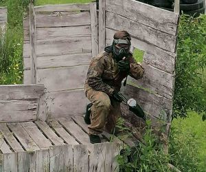 Uczeń w mundurze i z pistoletem schowany za drewnianą ścianą