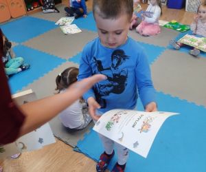 Chłopiec odbiera dyplom od nauczycielki