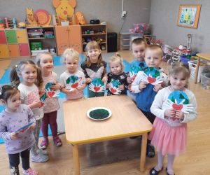 Przedszkolaki dookoła stołu, w rękach mają laurki w kształcie planety Ziemi. Na stole miniatura Ziemi.