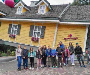 Grupa uczniów z nauczycielką przy odwróconej chatce