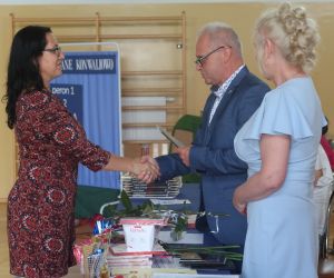 Pan dyrektor wręcza list gratulacyjny kobiecie - rodzic uczennicy klasy ósmej.