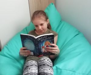 Dziewczynka czytająca książkę na fotelu