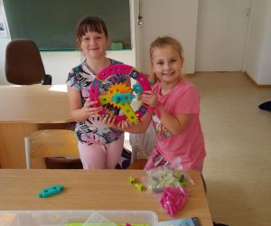Dwie dziewczynki z klasy drugiej ze zbudowaną przez siebie zębatką z klocków