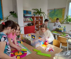 Uczniowie klasy drugiej przy stolikach budują konstrukcje z klocków