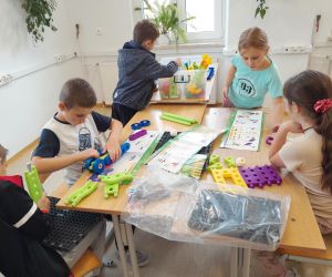 Czworo uczniów przy stoliku buduje konstrukcje z klocków