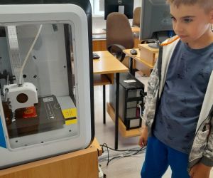 Uczeń klasy drugiej obserwuje działanie drukarki 3D