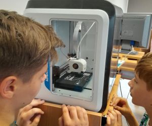 Uczniowie obserwują etapy wydruku breloka