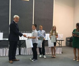 Uczeń odbiera upominek od senatora