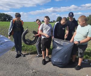 Uczniowie wrzucają do worków znalezione śmieci