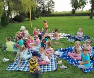 Dzieci spożywają posiłek na kocach piknikowych