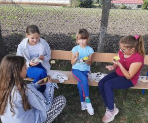 Uczennice siedzą na ławce i jedzą pieczone ziemniaki